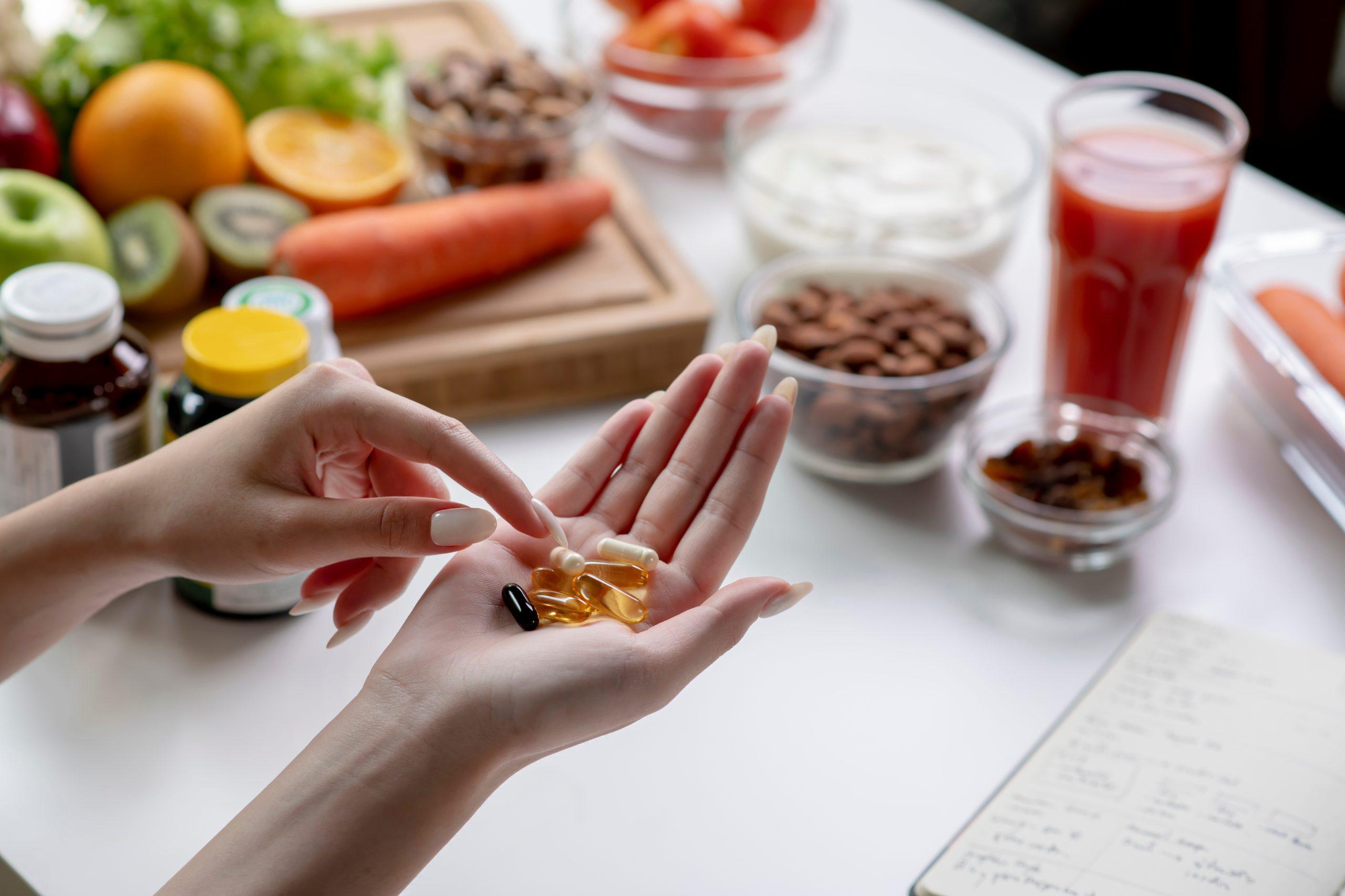 Woman holding dietary supplements above a table, highlighting fertility support and overall wellness in her daily routine.