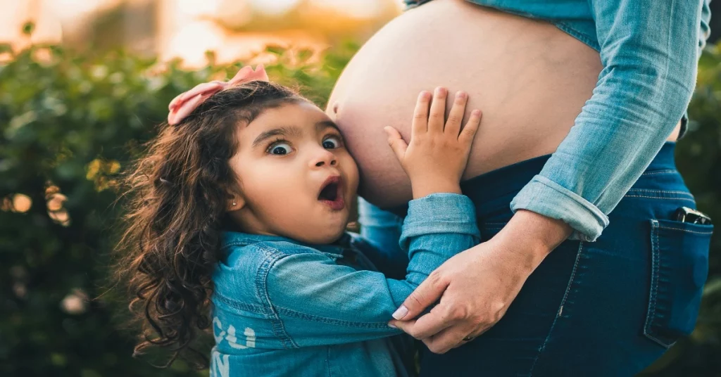 Un enfant touche le ventre dâune personne enceinte, capturant la magie de tomber enceinte rapidement dans la verdure.